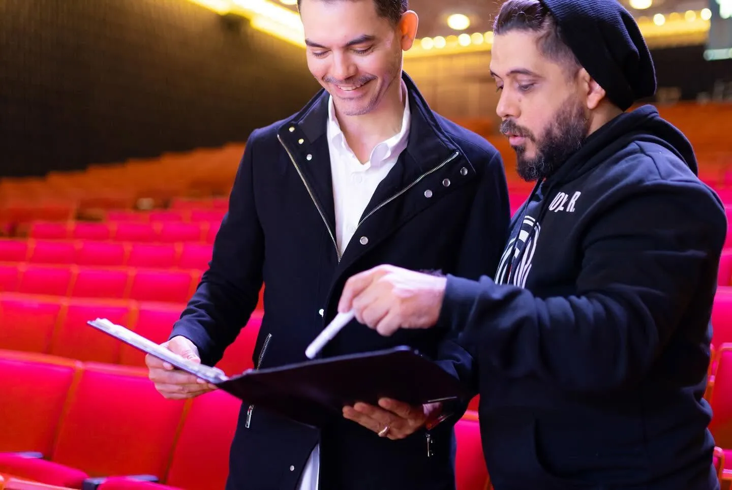 Camilo Then revisa el libreto del evento con un colaborador en la sala del teatro